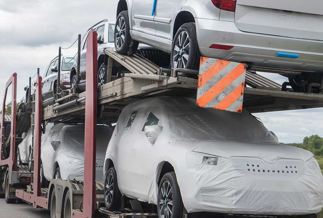 In Schutzfolie verpackte Autos auf einem Bahnanhänger während des Transports.