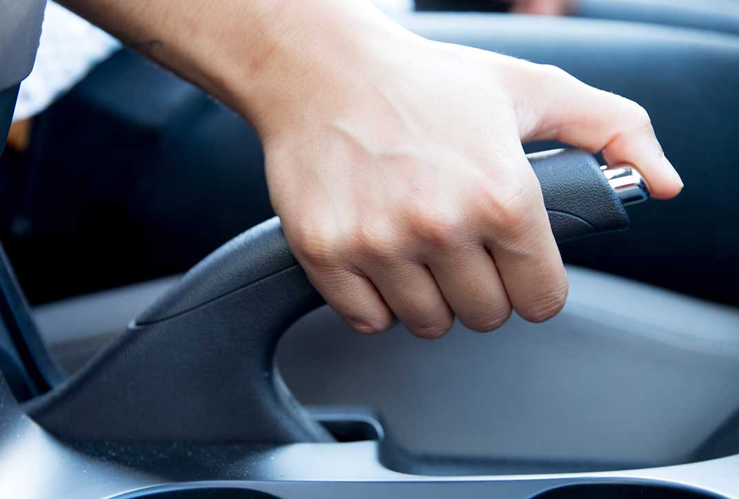 A hand applying the parking brake in a car.