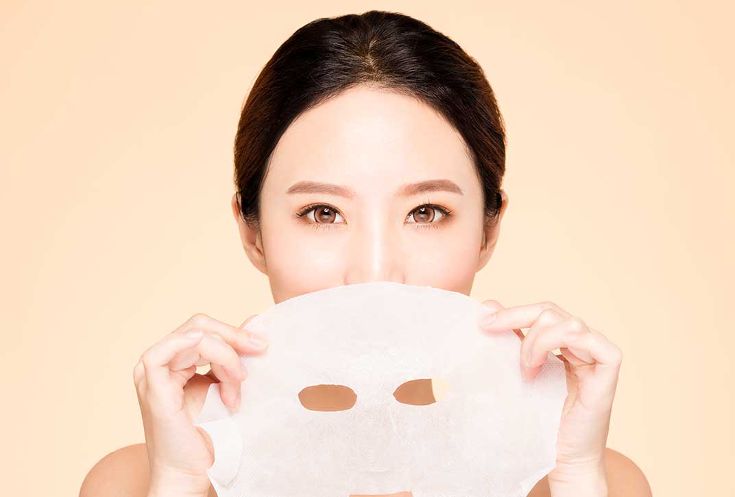A lady using a fabric-based facial mask.