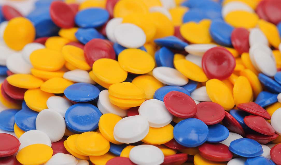 Some plastic pellets in different colors: red, yellow, blue and white.