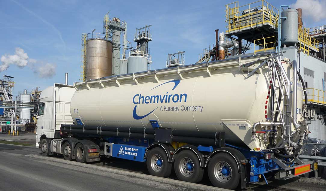 A truck with the “Chemviron” logo. In the background is a chemical plant.