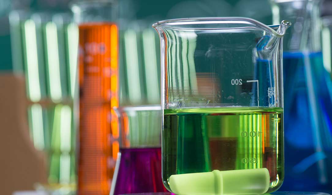 Verschiedene Laborgläser aus dem Chemielabor mit verschiedenfarbigen Flüssigkeiten.