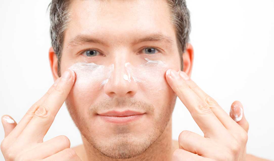 A man is applying cream to his face. The cream has not yet been completely absorbed.
