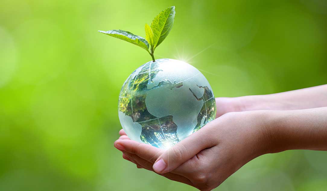 Woman holding a globe with a green leaf in her hands