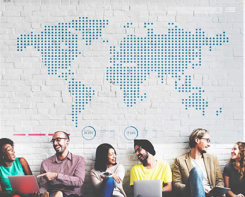 Group of internationals sitting in front of a world map. 